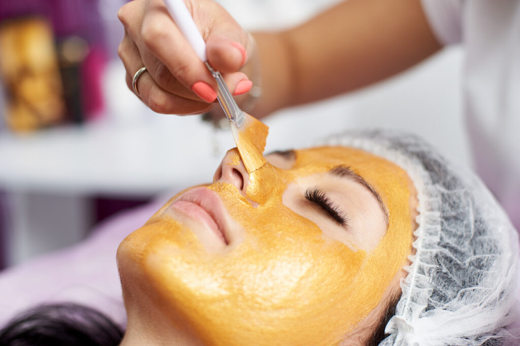 Esthetician applying a 24K gold facial mask at KL Beauty Salon in San Jose